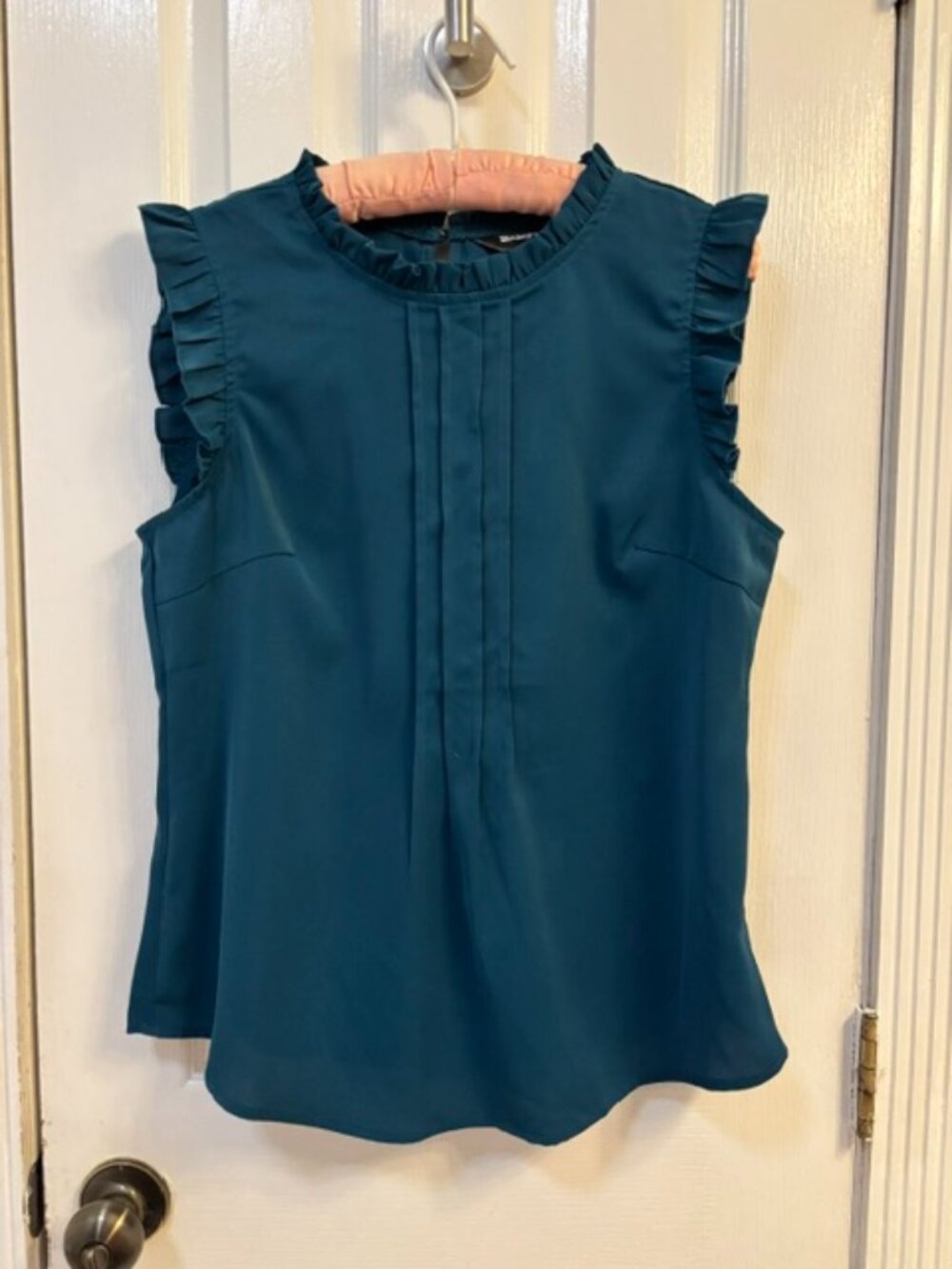 Dark teal blouse with single button closure.